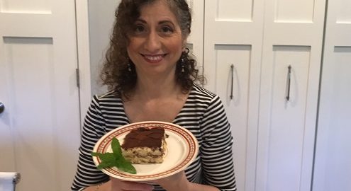 Kathryn Occhipinti holding a plate with a slice of Tiramisu and mint garnish