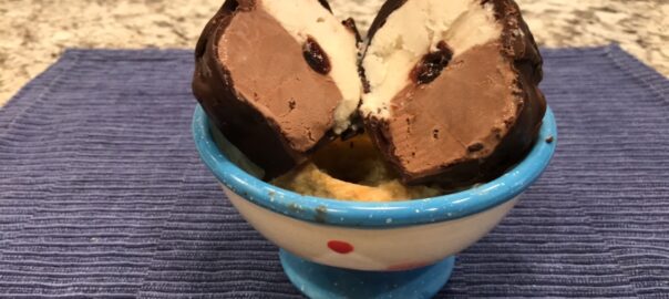 bowl with a tartufo ball cut in half so the vanilla/chocolate ice cream sides are showing with a cherry in the center.